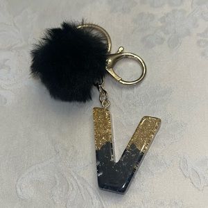 Bag charm or keychain with pom pom. Colors are black and gold